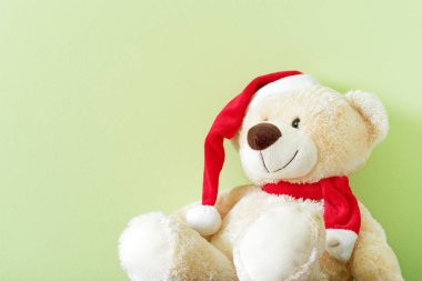 Kırmızı Noel şapkalı oyuncak ayı açık yeşil arka planda