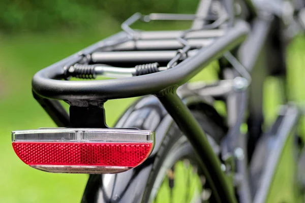 Крупный План Красного Отражателя Черном Велосипеде Против Зеленого Луга — стоковое фото
