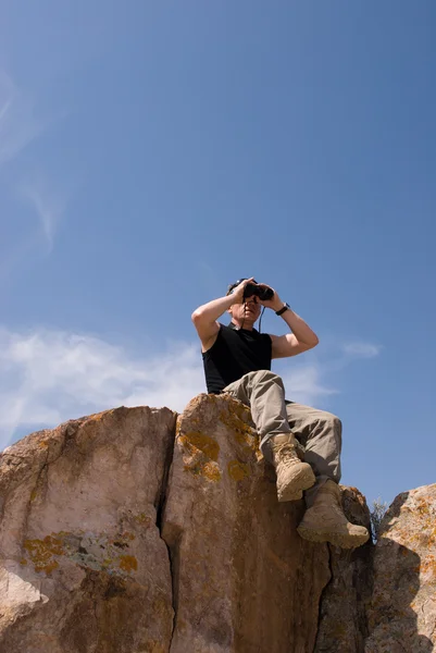 Man looks into binoculars — Stock Photo, Image
