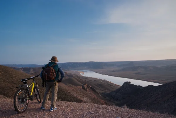 The bicyclist looks downwards at the river — Stock Photo, Image