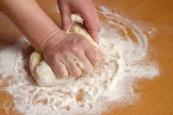 As mãos do padeiro amassam a massa de farinha — Fotografia de Stock