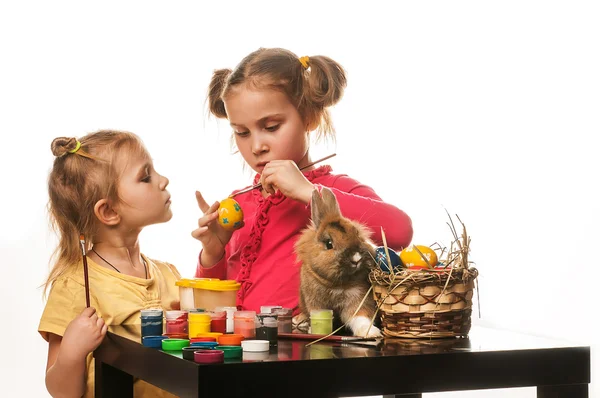 Twee kleine meisjes om te schilderen van Pasen eieren op een witte achtergrond — Stockfoto