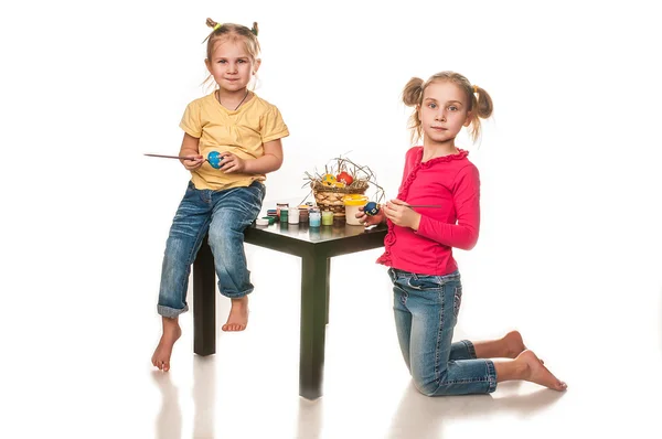 Two little girls to paint Easter eggs on a white background — Stock Photo, Image