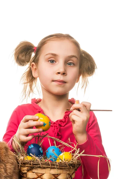 Little girl drawing on the Easter eggs on a white background — Stock Photo, Image