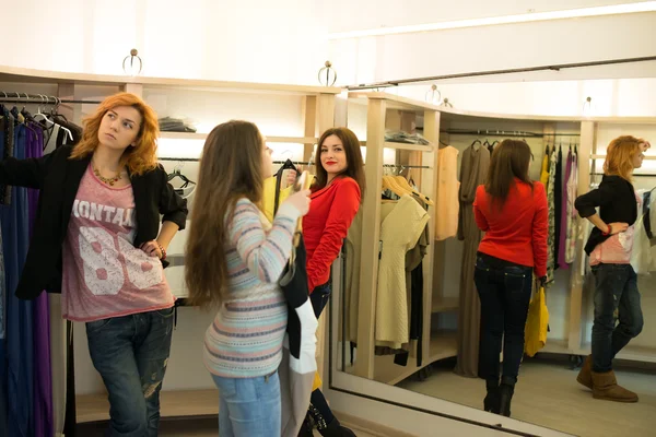 Mulher compras escolhendo vestidos olhando no espelho incerto — Fotografia de Stock