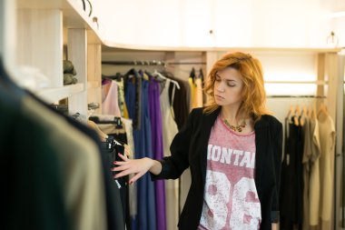Woman shopping choosing dresses looking in mirror uncertain