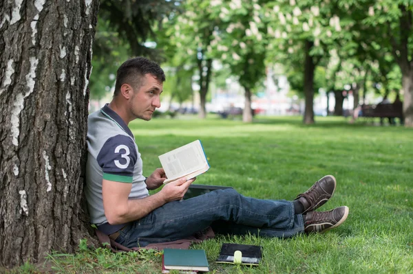 Student met skateboard en rugzak lezen — Stockfoto