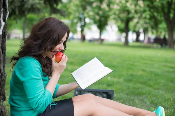 Mooi meisje leest boek in een park — Stockfoto