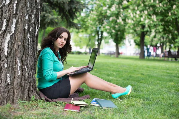 The beautiful young woman sits on a grass — Stock Photo, Image