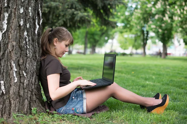 Die schöne junge Frau sitzt auf einem Gras — Stockfoto