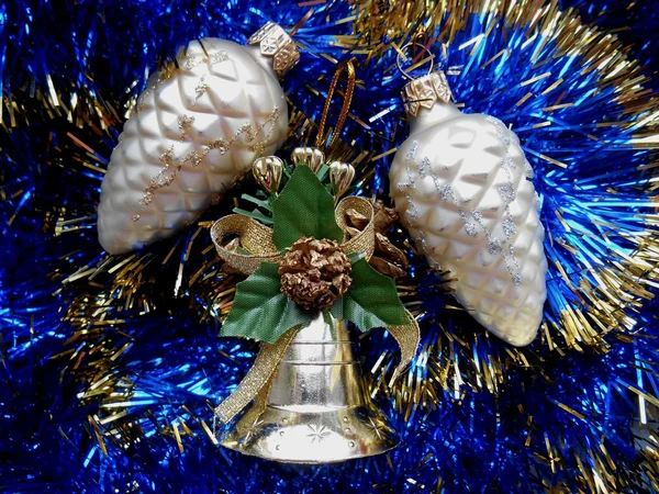 Boże Narodzenie i nowy rok ozdoba dzwon i sosnowych szyszek na niebieskim tle blichtr — Zdjęcie stockowe
