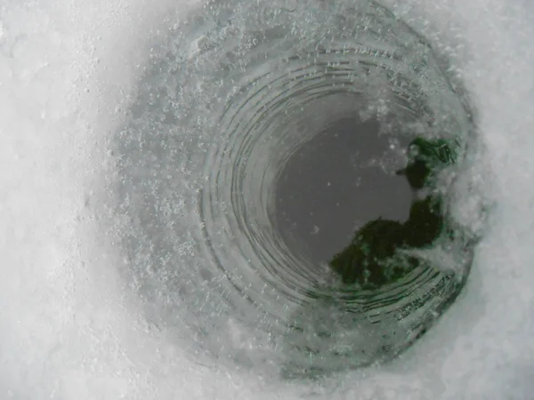 在冰上冬季捕鱼钓鱼洞 免版税图库照片