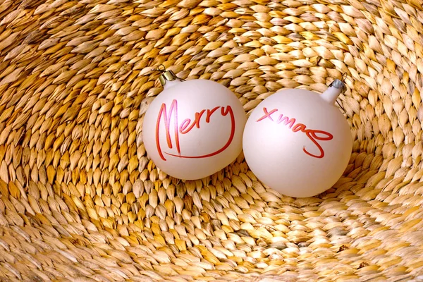 Deux boules avec des mots "Joyeux Noël" sur panier tissé de vigne Images De Stock Libres De Droits