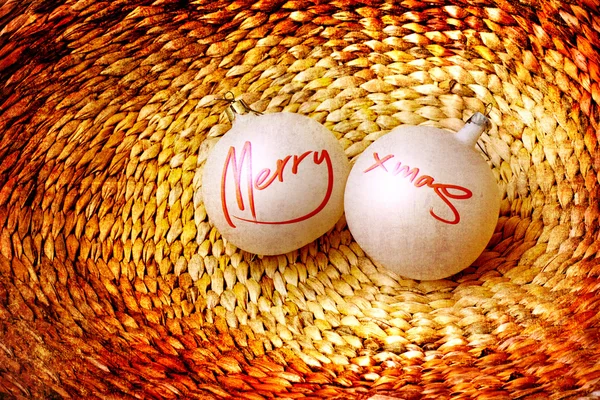 Deux boules avec des mots "Joyeux Noël" sur panier tissé de vigne Photos De Stock Libres De Droits