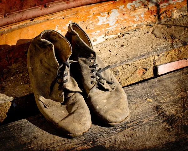 Viejas botas sucias. Botas viejas usadas con arañazos y cordones de zapatos desatados sobre fondo grunge — Foto de Stock