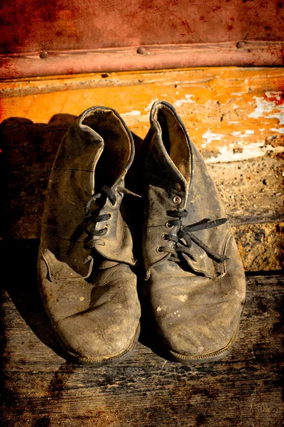 Viejas botas sucias. Botas viejas usadas con arañazos y cordones de zapatos desatados sobre fondo grunge — Foto de Stock
