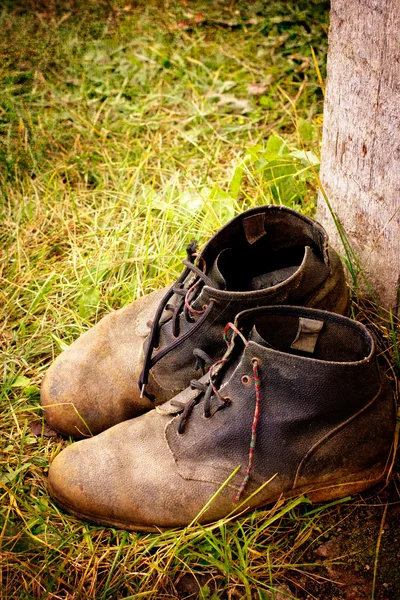 Viejas botas sucias. Botas viejas usadas con arañazos y cordones de zapatos desatados sobre fondo grunge — Foto de Stock