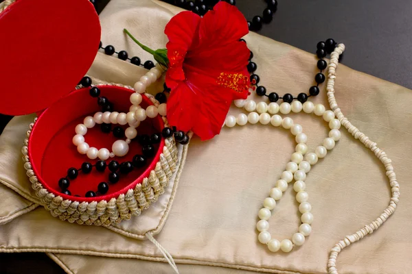 Perlenkette mit roter Blume auf dem schwarzen Tisch — Stockfoto