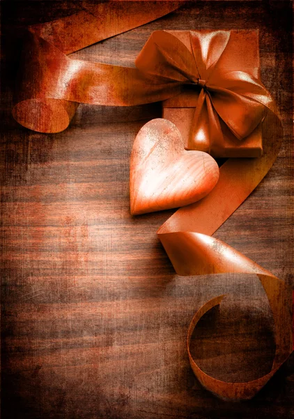 Sztuka wakacje prezent z kokardą z wstążki i serca na tle drewniane — Zdjęcie stockowe