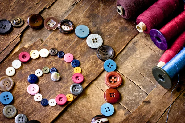 Spools of threads and buttons on old wooden table — Stock Photo, Image