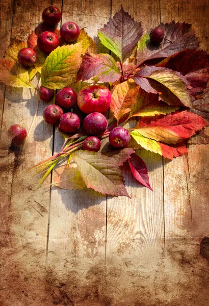 Bordo d'autunno d'annata da mele e foglie cadute su vecchio tavolo di legno — Foto Stock