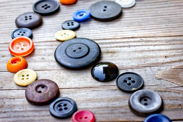 Набор винтажных кнопок на старом деревянном столе — стоковое фото