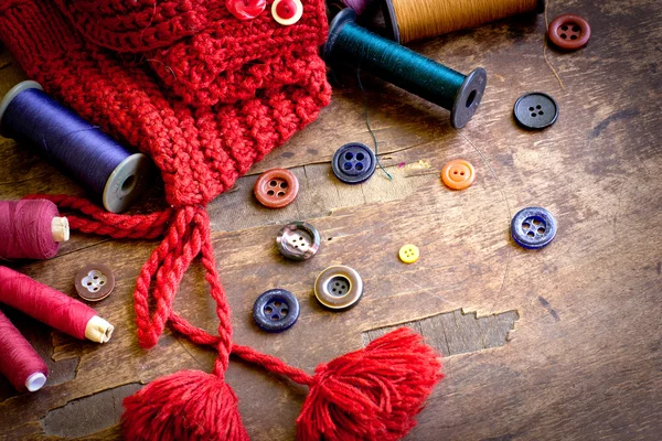 Set of spools of threads vintage buttons with knitted cap on old wooden table — Stock Photo, Image