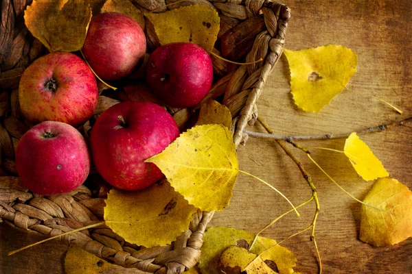 每蒲式耳的红苹果和秋天的树叶 — 图库照片