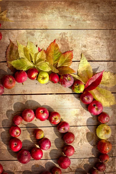 Vintage frontera de otoño de manzanas y hojas caídas en la vieja mesa de madera . —  Fotos de Stock