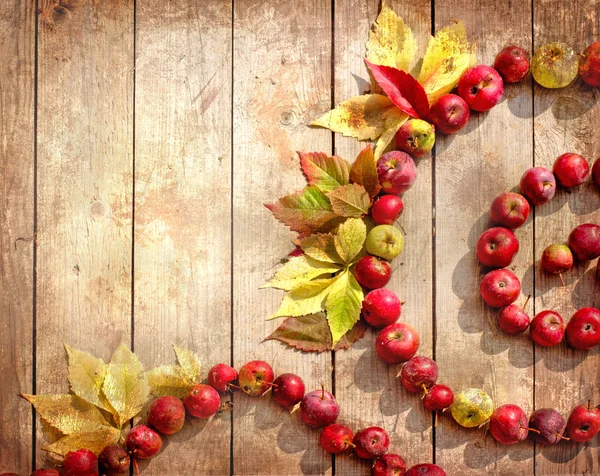 Vintage frontera de otoño de manzanas y hojas caídas en la vieja mesa de madera . — Foto de Stock