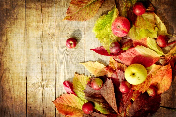 Vintage frontera de otoño de manzanas y hojas caídas en la vieja mesa de madera Fotos de stock libres de derechos