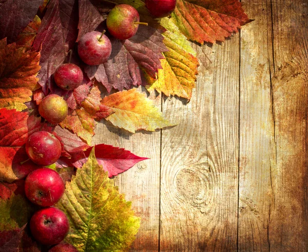 从苹果和落叶在旧木桌上的老式秋季边框 — 图库照片#