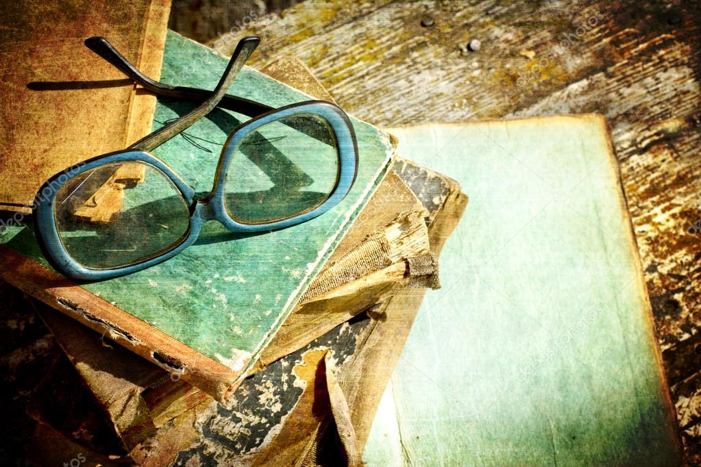 Close-up of opened book pages and glasses against vintage background.