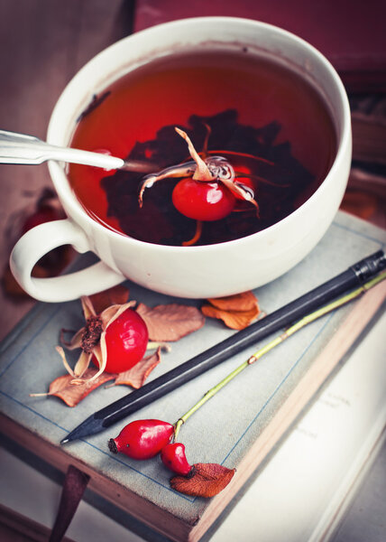 Чашка чая из шиповника на старых книгах
