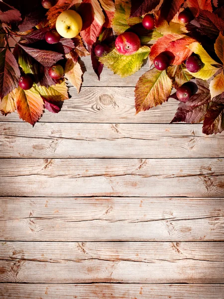 Appels en gevallen bladeren op oude houten tafel — Stockfoto