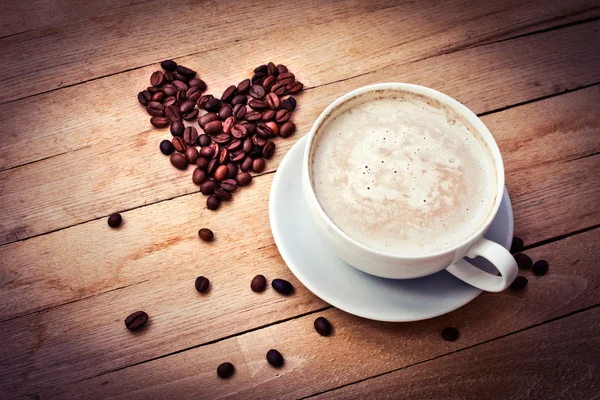 Xícara de café e coração de grãos de café — Fotografia de Stock