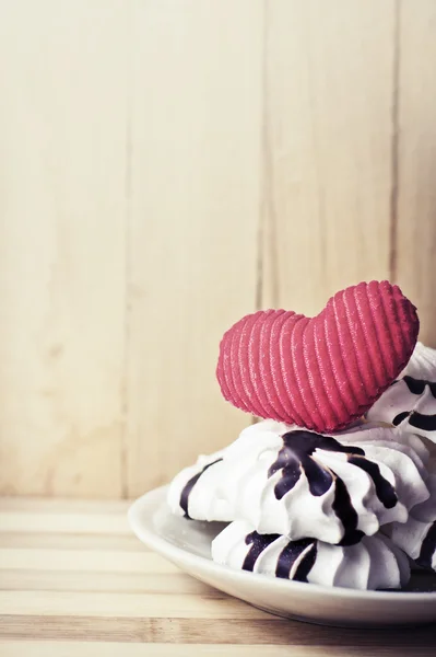 Galletas de merengue en platillo y corazón rojo —  Fotos de Stock