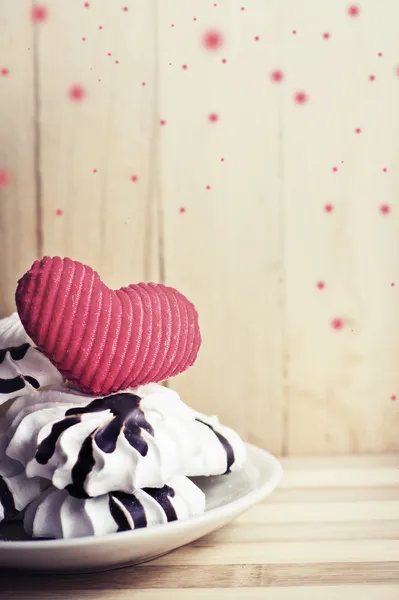 Galletas de merengue en platillo y corazón rojo —  Fotos de Stock