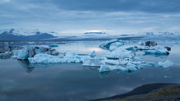 Blue icebergs floating under midnight sun