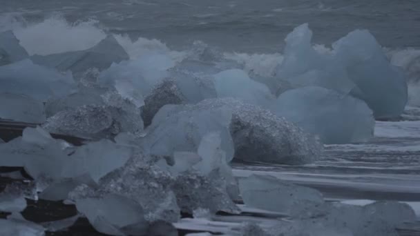 Increíbles icebergs y olas sobre la playa de arena negra — Vídeo de stock