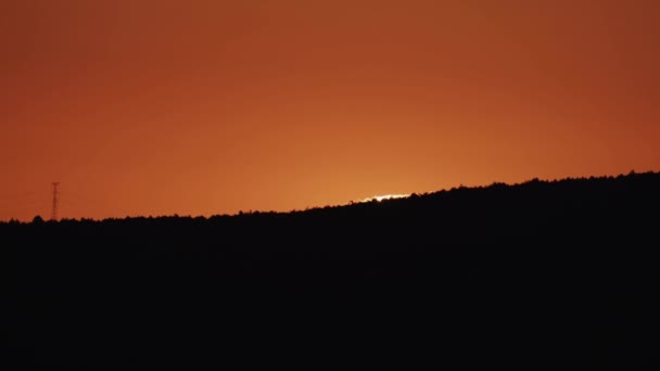 Słońce wschodzące nad sylwetką wzgórza, pomarańczowe niebo — Wideo stockowe