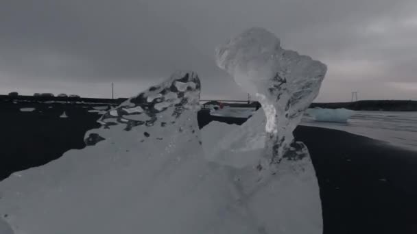 Дивовижний айсберг і турист над пляжем чорного піску — стокове відео