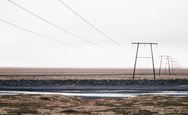 Ufukta kaybolan beyaz gökyüzünün altındaki elektrik hatları