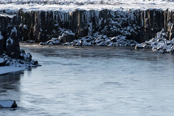Rochers cubiques au bord de la rivière recouverts de neige — Photo