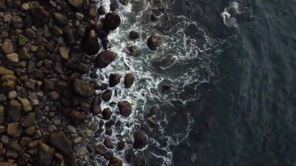 Blick von oben auf Wellen, die über runde Felsen brechen — Stockvideo