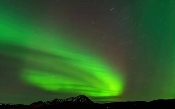 Aurora borealis Langzeitbelichtung mit Sternpfad und Berggipfel — Stockfoto