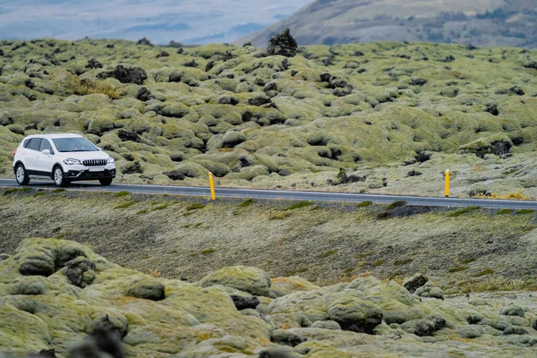 Witte auto rijdt door lavavelden bedekt met mos — Stockfoto