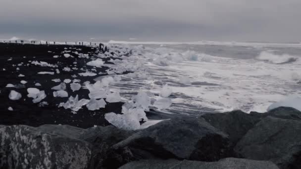 Spectaculaire golven breken over enorme ijsbergen op diamant strand met toeristen — Stockvideo