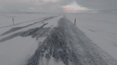 Rüzgarlı bir günde karla kaplı bir yol.