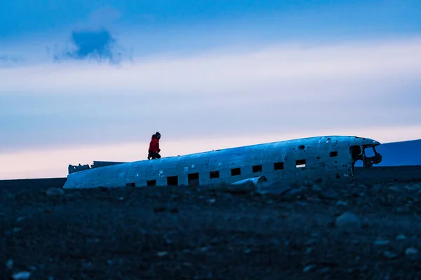 Wrak van een vliegtuig met toerist bovenop bij zonsondergang — Stockfoto